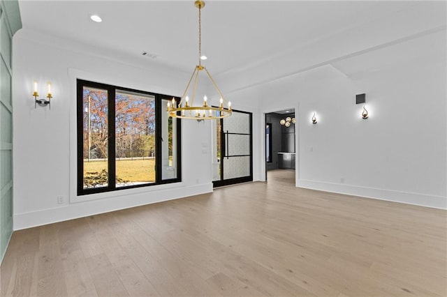 unfurnished dining area with an inviting chandelier and light wood-type flooring