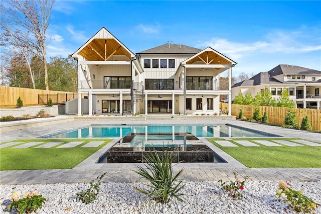 back of property featuring a fenced in pool, ceiling fan, a balcony, and a patio