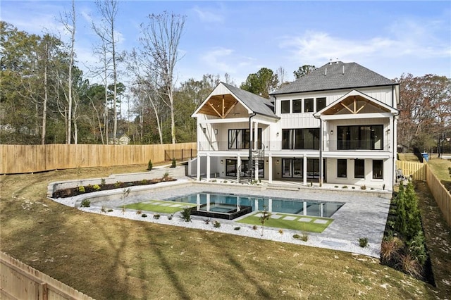 back of property with a patio area, a balcony, and a pool with hot tub