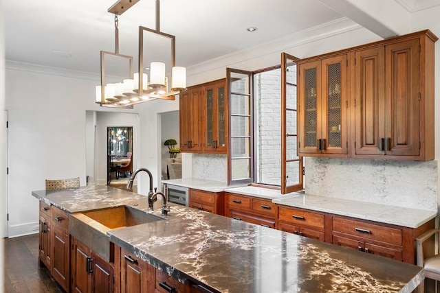 kitchen featuring pendant lighting, a sink, glass insert cabinets, and brown cabinets