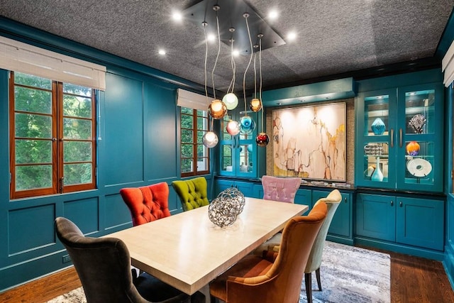 dining space with a decorative wall and dark wood-type flooring