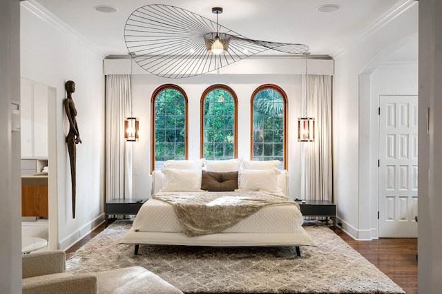 bedroom with baseboards, arched walkways, dark wood finished floors, and crown molding