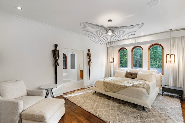 bedroom with crown molding, arched walkways, wood finished floors, and recessed lighting