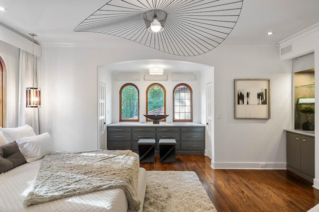 bedroom featuring dark wood-style floors, arched walkways, visible vents, ornamental molding, and baseboards