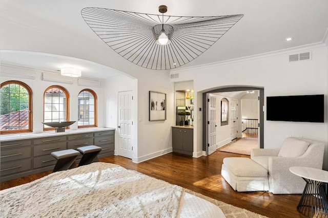 bedroom with dark wood-style floors, visible vents, arched walkways, and crown molding