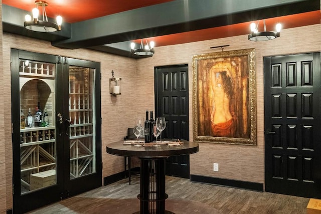 wine room featuring a chandelier, french doors, wood finished floors, and baseboards