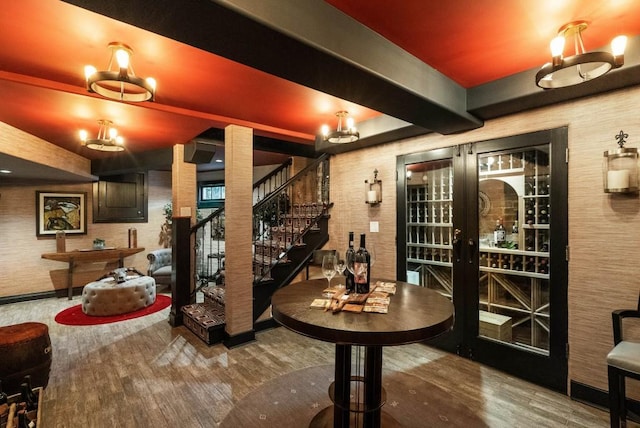 wine cellar featuring beam ceiling, french doors, and wood finished floors