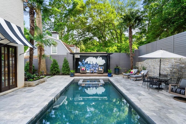 view of swimming pool featuring a pool with connected hot tub, a fenced backyard, a patio, and french doors