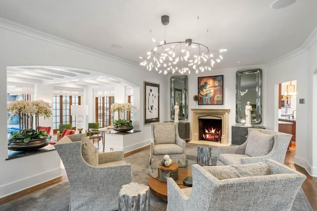 sitting room with arched walkways, crown molding, wood finished floors, a warm lit fireplace, and baseboards