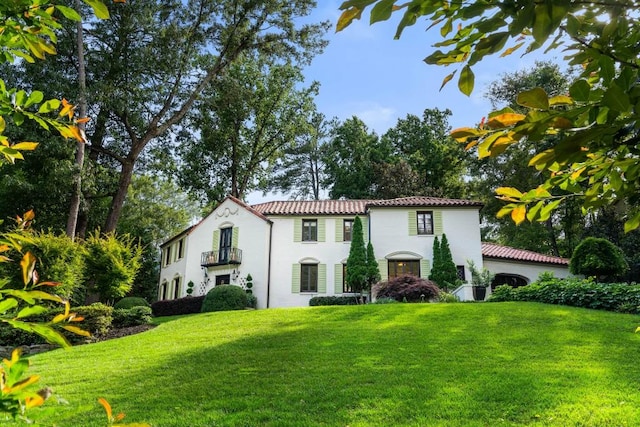 mediterranean / spanish-style house featuring a tiled roof and a front yard