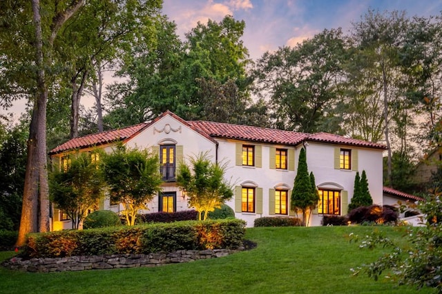 mediterranean / spanish-style home with a front yard, french doors, a tile roof, and stucco siding