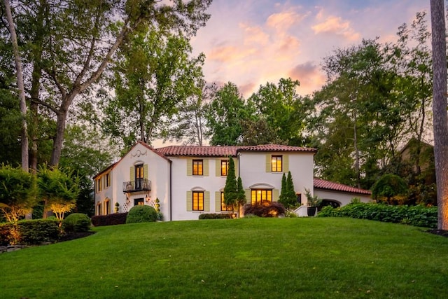 mediterranean / spanish-style home featuring a tiled roof, a yard, and a balcony