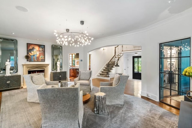 interior space with arched walkways, stairway, ornamental molding, wood finished floors, and a lit fireplace