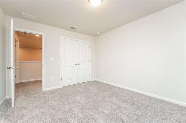 unfurnished bedroom with light colored carpet and a closet