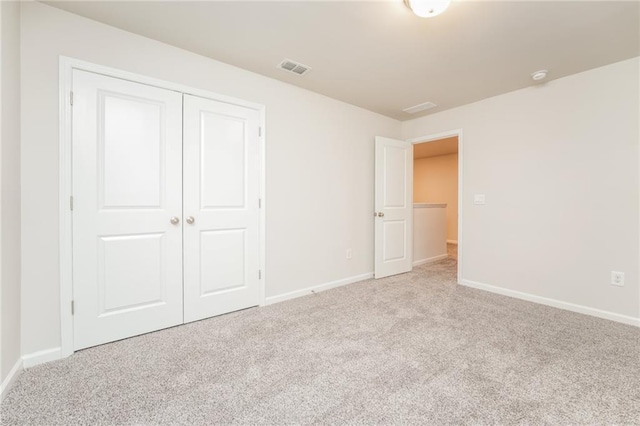 unfurnished bedroom featuring a closet and light colored carpet