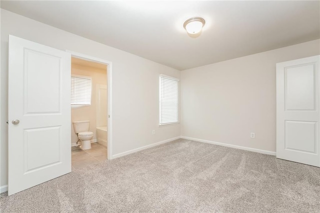 unfurnished bedroom with light colored carpet and ensuite bathroom