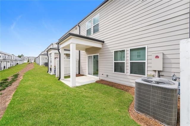 back of property with central AC unit and a yard