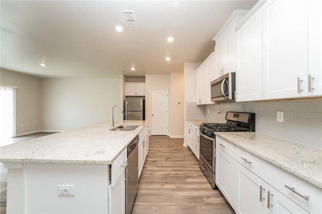 kitchen with sink, white cabinets, stainless steel appliances, and a kitchen island with sink