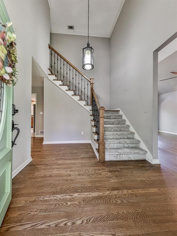 stairs with a towering ceiling, wood-type flooring, and ornamental molding