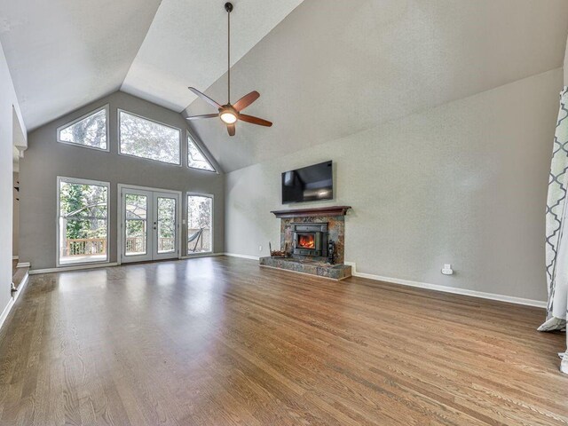 unfurnished living room with hardwood / wood-style floors, ceiling fan, high vaulted ceiling, and french doors