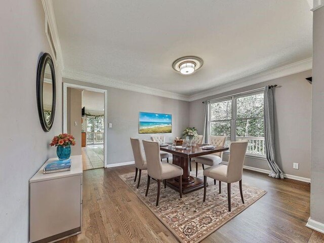 dining space featuring hardwood / wood-style floors and ornamental molding