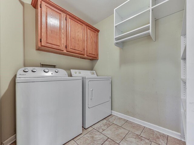 laundry area with cabinets, light tile patterned flooring, and washing machine and dryer