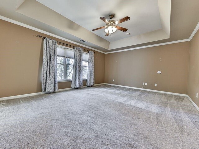 spare room with a raised ceiling, crown molding, carpet, and ceiling fan