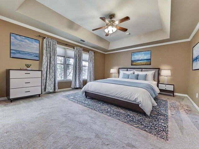 carpeted bedroom featuring a tray ceiling, ceiling fan, and ornamental molding