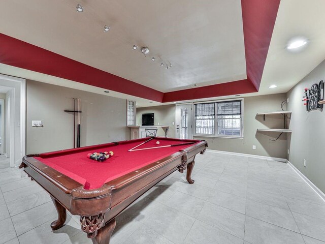 recreation room with a tray ceiling, light tile patterned floors, and billiards