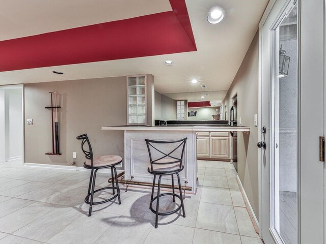 kitchen featuring kitchen peninsula, light brown cabinets, and a breakfast bar area