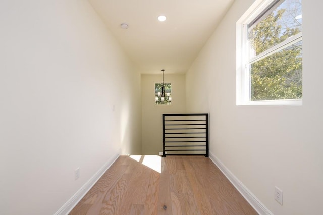 stairs featuring plenty of natural light, hardwood / wood-style floors, and a notable chandelier