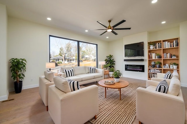 living room with light hardwood / wood-style floors and ceiling fan