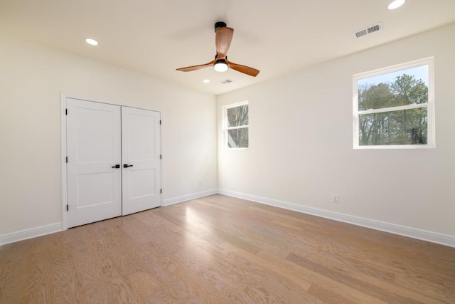 unfurnished bedroom featuring multiple windows, light hardwood / wood-style floors, and ceiling fan