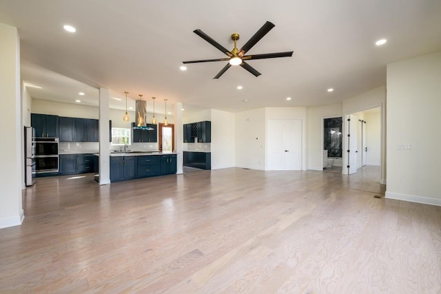 unfurnished living room featuring ceiling fan, sink, and light hardwood / wood-style flooring