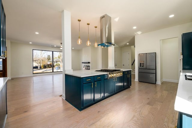 kitchen with blue cabinets, hanging light fixtures, island exhaust hood, stainless steel gas cooktop, and fridge with ice dispenser