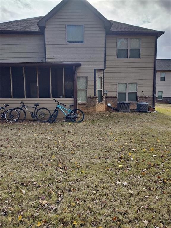 rear view of property featuring a sunroom and a yard