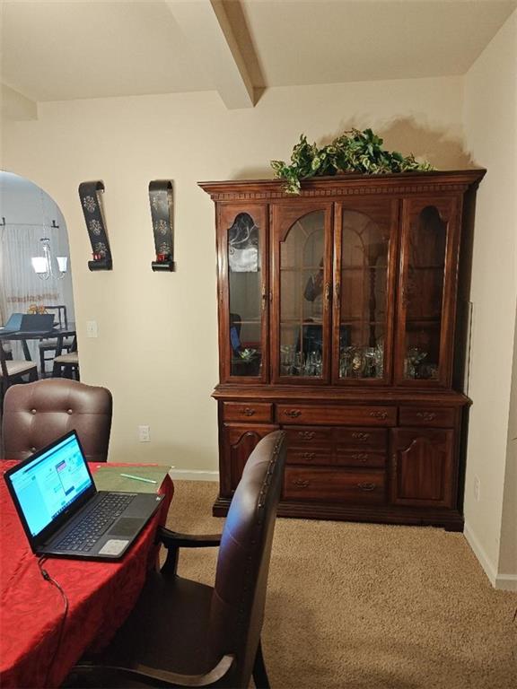 carpeted office space featuring beamed ceiling