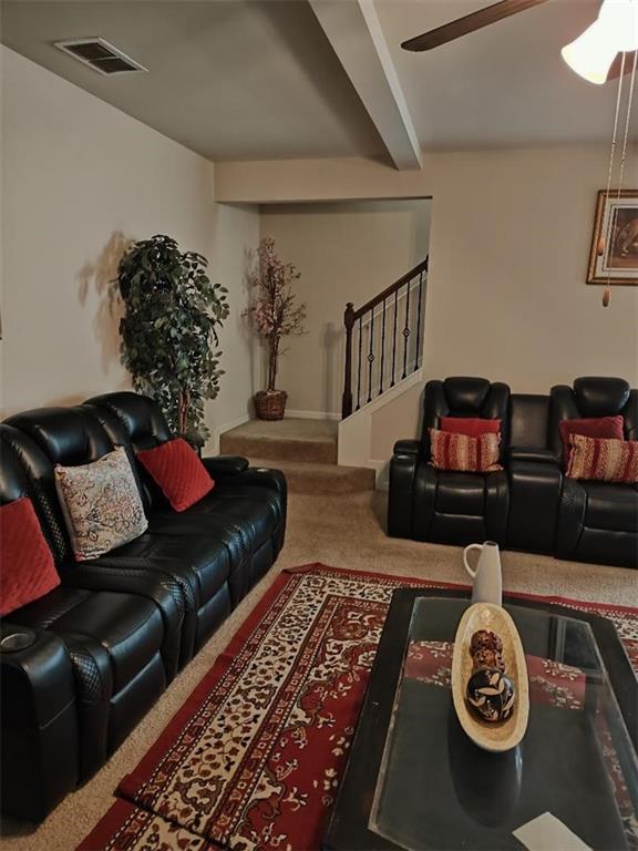 living room featuring ceiling fan, beamed ceiling, and carpet floors