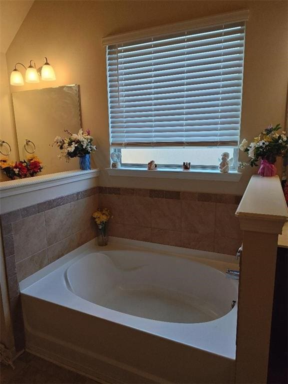 bathroom with a relaxing tiled tub and vaulted ceiling