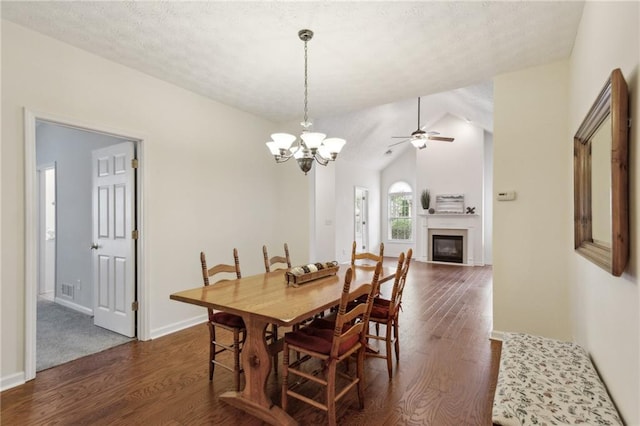 dining space featuring lofted ceiling, ceiling fan with notable chandelier, dark wood-type flooring, and a textured ceiling