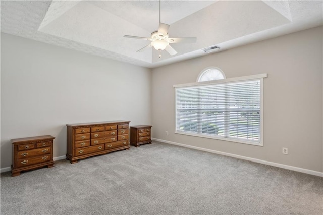 carpeted bedroom featuring ceiling fan and a tray ceiling