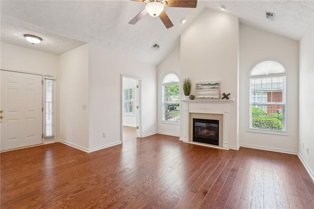 unfurnished living room featuring wood-type flooring, a healthy amount of sunlight, and a textured ceiling