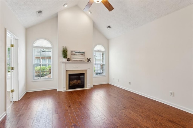 unfurnished living room featuring ceiling fan, high vaulted ceiling, dark hardwood / wood-style floors, and a textured ceiling