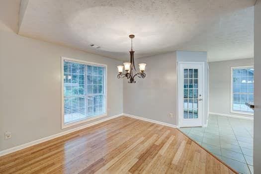 2105 Huntington Hills Trce, Buford, GA 30519 - unfurnished dining area with a chandelier, wood finished floors, and a textured ceiling
