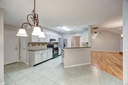 2105 Huntington Hills Trce, Buford, GA 30519 - kitchen with black range with electric cooktop, tasteful backsplash, decorative light fixtures, and white cabinets