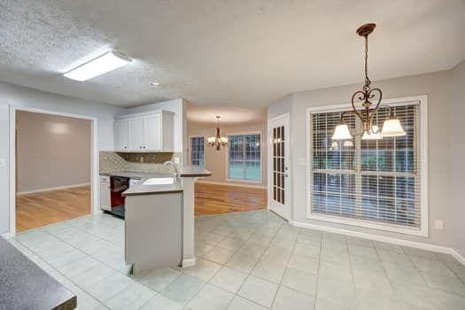 2105 Huntington Hills Trce, Buford, GA 30519 - kitchen featuring a chandelier, a peninsula, pendant lighting, white cabinetry, and tasteful backsplash