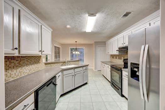 2105 Huntington Hills Trce, Buford, GA 30519 - kitchen with black appliances, under cabinet range hood, a textured ceiling, backsplash, and white cabinets
