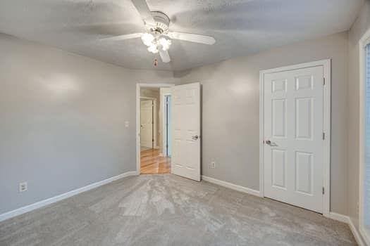 2105 Huntington Hills Trce, Buford, GA 30519 - unfurnished bedroom featuring ceiling fan and carpet flooring