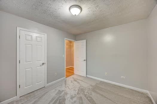 2105 Huntington Hills Trce, Buford, GA 30519 - unfurnished bedroom with a textured ceiling and baseboards