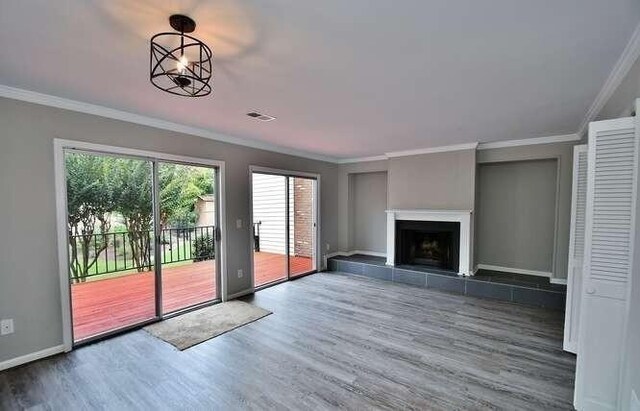 6500 Gaines Ferry Rd Unit A2, Flowery Branch, GA 30542 - unfurnished living room featuring wood finished floors, crown molding, a tile fireplace, and baseboards